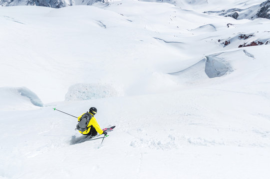 A skier at speed rides on a snowy slope freeride. The concept of winter extreme sports
