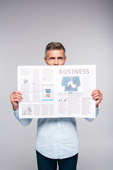 handsome adult businessman covering face with business newspaper isolated on white
