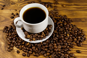 Cup of coffee and roasted coffee beans on wooden table