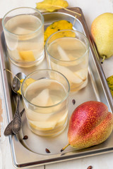 Homemade freshly made fruit compote from pears in small round glasses cups on a metal tray.