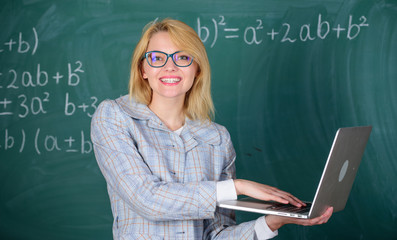 Educator smart clever lady with modern laptop searching information chalkboard background. Woman...