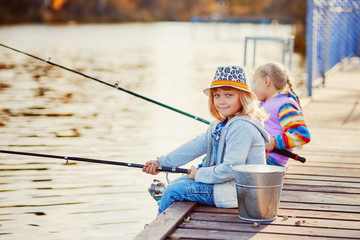 Two little girls fishing on the lake on a sunny morning.