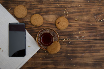 Smart phone tablet and biscuits with tea on the table