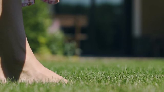 Woman walks on green grass in backyard enjoys contact with nature oneness senses