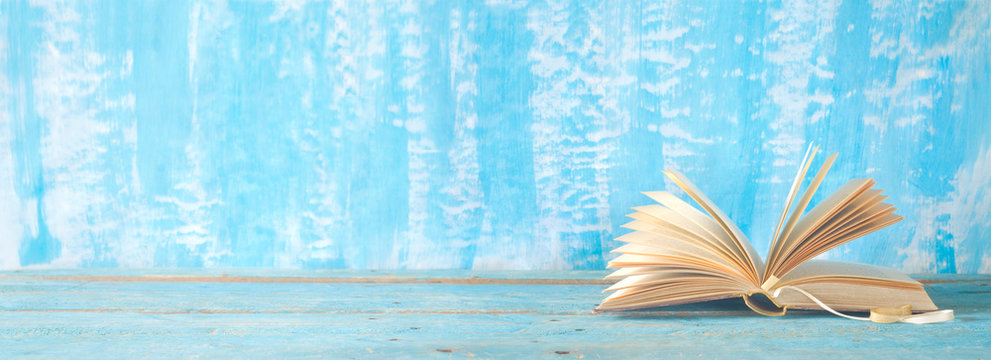 open book on blue paint background, panorama, reading, education, literature, good copy space