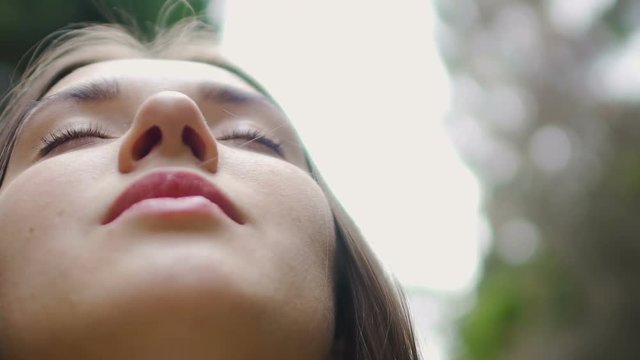 Low angle shot woman face with closed eyes meditates feels united with nature