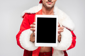 cropped shot of man in santa costume holding digital tablet with blank screen isolated on grey