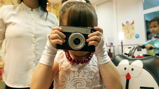Little girl taking picture on old photo camera