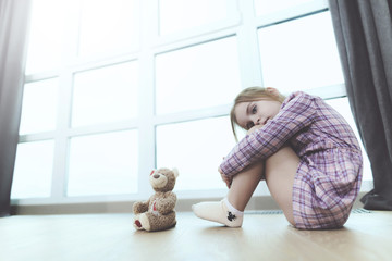 Sad Girl Sit with Teddy Bear on Floor Indoors