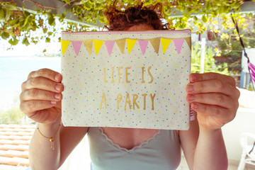 woman holding funny text/message to the camera, live is a party