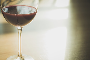 Red wine in wineglass against wooden background.