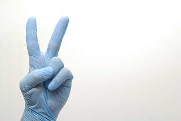 The surgeon's hand in a blue medical glove, showing a sign on an isolated background.