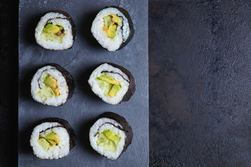 Vegan sushi rolls made with nori algae, sushi rice, cucumbers and avocado. Top view with copy space