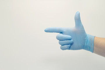 The surgeon's hand in a blue medical glove, showing a sign on an isolated background.