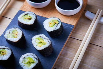 Fototapeta na wymiar Vegan sushi rolls made with nori algae, sushi rice, cucumbers and avocado