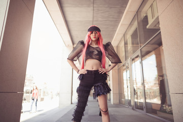 Japan anime cosplay. Colorful portrait of young attractive asian woman in sexy dress with creative make-up and wearing pink wig outdoors. Trendy Japanese girl posing outside on city street against