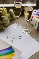 Close up photo of two glasses with champagne,postcard,wedding ring and lgbt sign isolated
