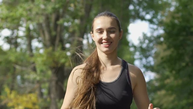 Smiling young woman runs in park, jogging in fresh air, enjoying sport lifestyle