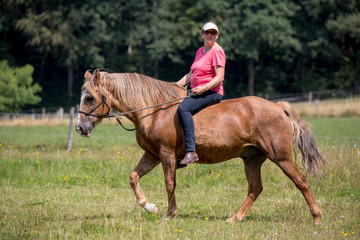 Frau reitet auf ihrem Pferd