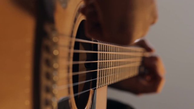 Close up shot of guitarist's hands plays chords on acoustic guitar at home