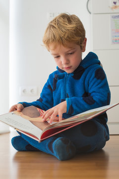Caucasian boy reading a book on the floor