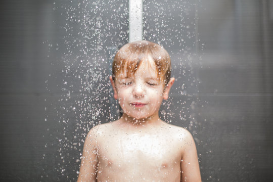 Caucasian boy playing in the shower