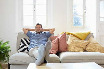 Man sitting on couch at home, relaxing