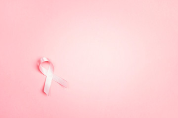 Pink ribbon on pink background with copy space. Breast cancer awareness symbol.