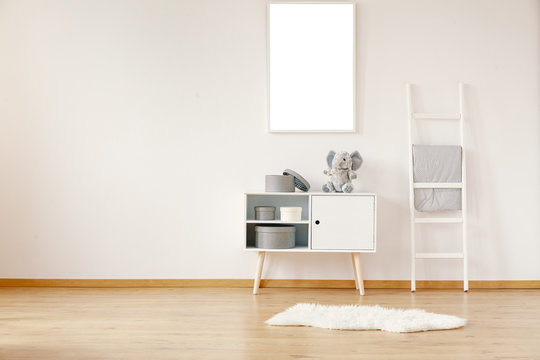 White wooden cabinet with teddy bear in spacious room with mockup on the wall