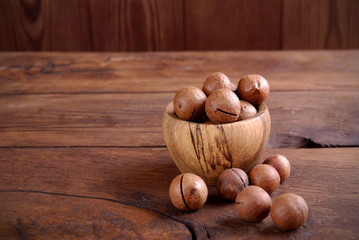 Macadamia nuts in a bowl on a wooden background.