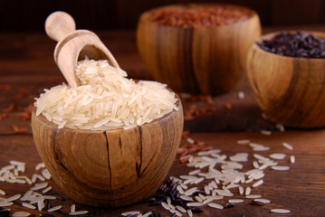 Fototapeta premium Brown, black and white rice in bowls on a wooden background.