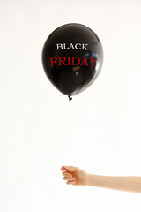 Obraz premium Black Friday on black balloon in girl's hand. Black friday sale concept. Fourth Friday of November, beginning of Christmas shopping season since 1952. Copy space, close up, top view, flat lay.