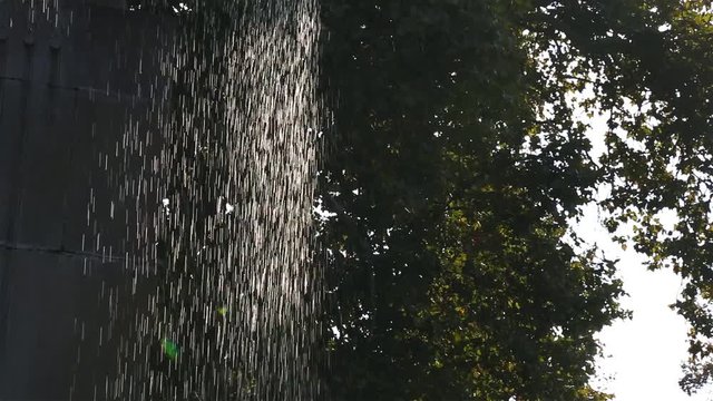 Drops of water pouring from a concrete city fountain close-up.