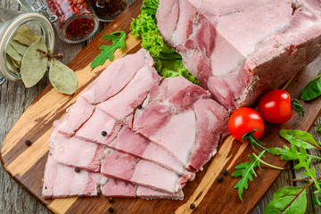 Roasted pork ham with kitchen knife and roast vegetables on dark rustic background