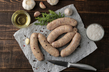Raw sausages with ingredients for cooking arugula, butter and garlic. on a brown wooden table. top view