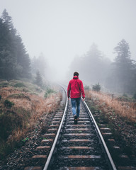 Wanderer läuft in roter Jacke über Schienen im Harz - obrazy, fototapety, plakaty
