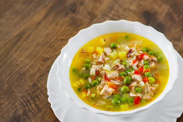 chicken soup with rice and vegetables in bowl on wooden table background