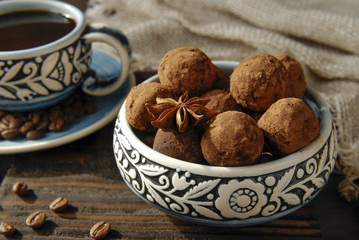 Truffle sweets in bowl and cup of coffee over wooden background.