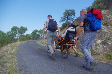 randonnée solidaire avec des gens qui aident des handicapés avec une joelette sur route