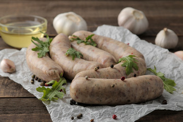 Raw sausages with ingredients for cooking arugula, butter and garlic. on a brown wooden table