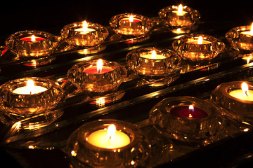 Coloured tealight candles in with flickering flames in crystal holders - obrazy, fototapety, plakaty