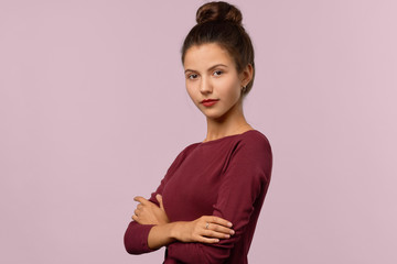 Confident attractive girl posing half turn folded hands on chest. Serious expression and hairstyle...