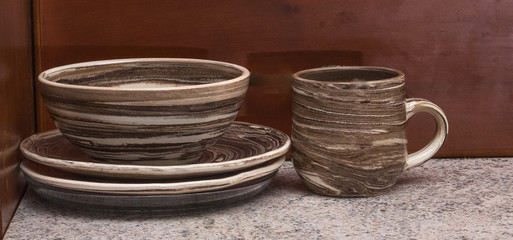 classic Greek clay bowl , cup and dish of red and white clay on a brown-gray background, handmade and an original rustic style in design