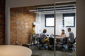 Young businesswoman giving a presentation to her colleagues at modern meeting room.