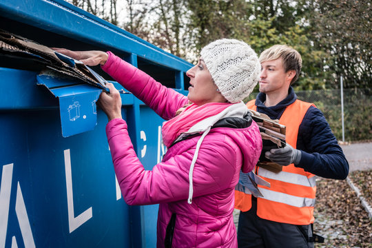 Frau und Mann entsorgen Altpapier in Container