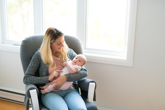 Young mother holding her newborn child on the chair