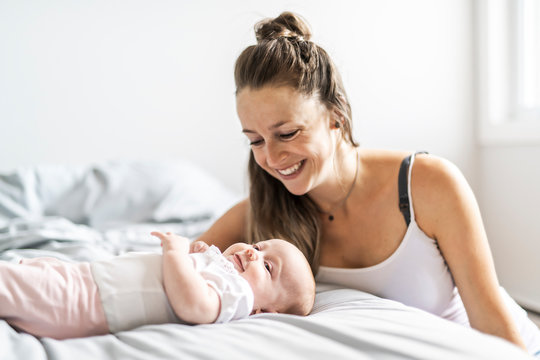 Portrait of a beautiful mother with her 2 month old baby in the bedroom