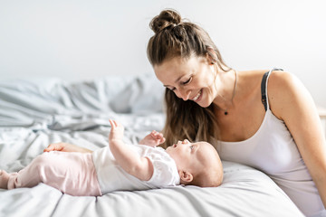Portrait of a beautiful mother with her 2 month old baby in the bedroom