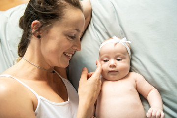 Portrait of a beautiful mother with her 2 month old baby in the bedroom