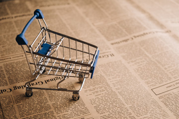 Empty shopping cart on newspaper background with copy space for text, Shoping online concept.